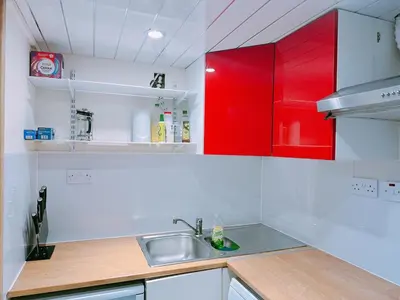 a kitchen with red cabinets and a sink at The Comfy Lofty Studio - R9 in Liverpool