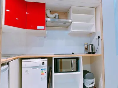 a small kitchen with red cabinets and a white refrigerator at The Comfy Lofty Studio - R9 in Liverpool