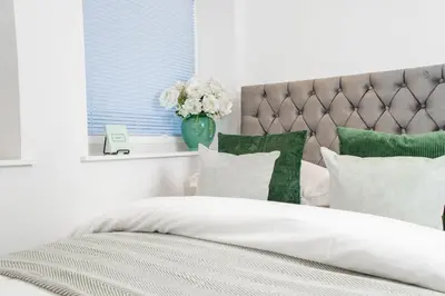 a bed with green and white pillows and a vase with flowers at Luxury Apartment - Sleeps 5 - Rose Platinum Properties in Liverpool