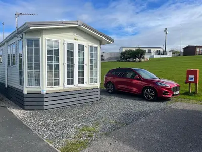 a red car parked next to a tiny house at Willow summer house in Heysham