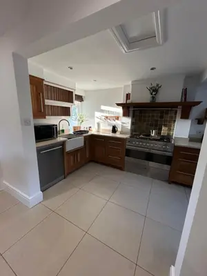 a large kitchen with wooden cabinets and a tile floor at The Willows in Whalley