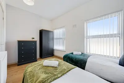 a white bedroom with two beds and a window at Thirlmere House - Air Host & Stay - 5 Bedrooms in Liverpool