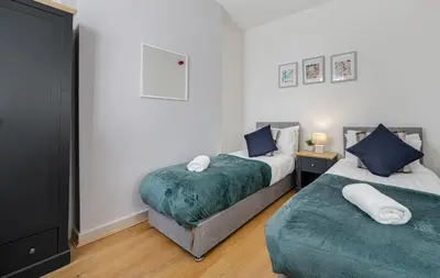 a bedroom with two beds with blue pillows at Thirlmere House - Air Host & Stay - 5 Bedrooms in Liverpool