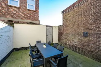 a table and chairs on a patio with a brick wall at Thirlmere House - Air Host & Stay - 5 Bedrooms in Liverpool