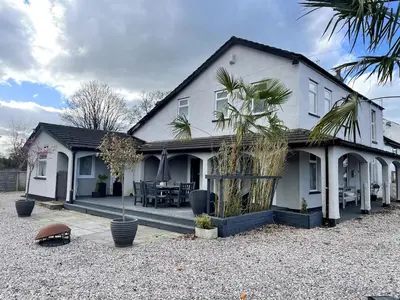 a white house with a palm tree in front of it at The Old Nursery in Blackburn