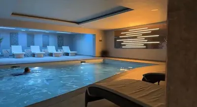 a pool in a hotel with a person swimming in it at Poppy Cottage, Mawdesley Village in Mawdesley