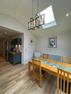 a dining room with a table and a kitchen at Poppy Cottage, Mawdesley Village in Mawdesley