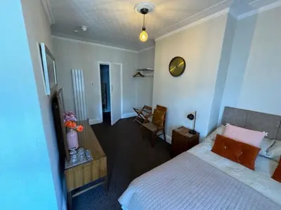 a bedroom with a bed and a room with a chair at The Golden Sands in Blackpool