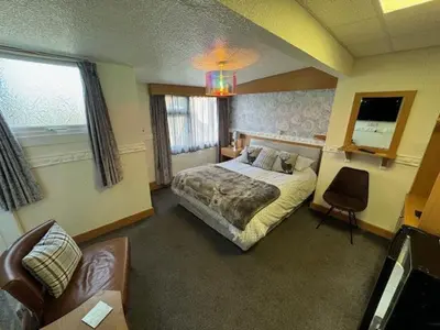 a bedroom with a bed and a chair and a couch at The Golden Sands in Blackpool