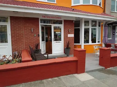a red brick building with a front porch and a store at The Golden Sands in Blackpool