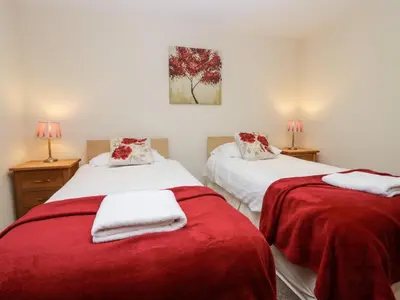 a bedroom with two beds with red blankets at 4 Teal House in Carnforth