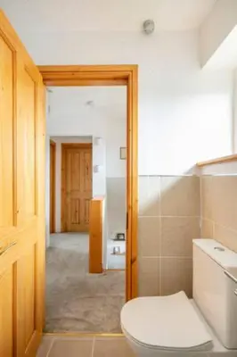 a bathroom with a white toilet and a hallway at Bright Double Room, Smart TV, Very Close to Train Station in Egerton