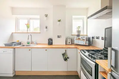 a kitchen with white cabinets and a stove top oven at Bright Double Room, Smart TV, Very Close to Train Station in Egerton