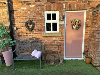 a brick house with a bench and a pink door at Luxury two bedroom Loft in Croston