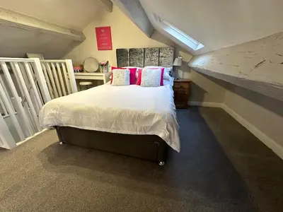 a bedroom with a bed with white sheets and pink pillows at Luxury two bedroom Loft in Croston