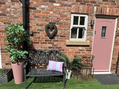 a bench in front of a brick building with a pink door at Luxury two bedroom Loft in Croston
