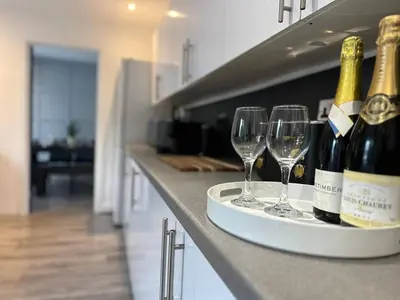 two wine bottles and glasses on a counter in a kitchen at Spacious 5 bedroom house in Fazakerley
