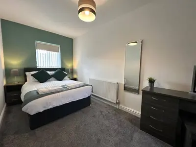 a bedroom with a bed with a mirror and a dresser at Spacious 5 bedroom house in Fazakerley