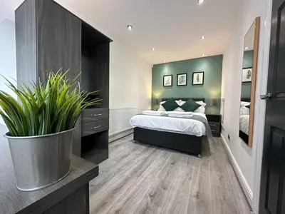 a bedroom with a bed and a large potted plant at Spacious 5 bedroom house in Fazakerley