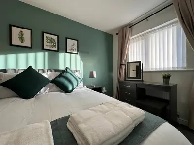 a bedroom with a bed and a desk and a window at Spacious 5 bedroom house in Fazakerley