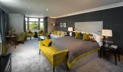 a bedroom with a large bed and a yellow couch at Northcote in Langho