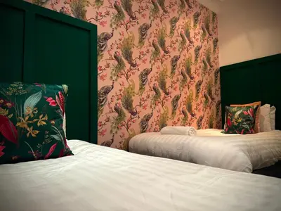 a bedroom with two beds and a floral wallpaper at Sleeps10-Parking-Garden-HotTub-PetFriendly in Blackpool