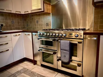 a kitchen with a stainless steel stove and white cabinets at Sleeps10-Parking-Garden-HotTub-PetFriendly in Blackpool