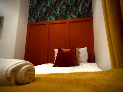 a bed with a red headboard and a red pillow at Sleeps10-Parking-Garden-HotTub-PetFriendly in Blackpool