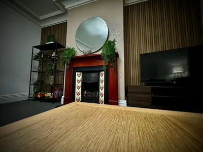 a living room with a fireplace and a mirror at Sleeps10-Parking-Garden-HotTub-PetFriendly in Blackpool