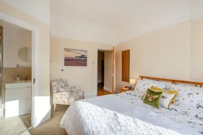 a white bedroom with a bed and a chair at 3 Bed in Lytham St. Annes oc-m30622 in Saint Annes on the Sea