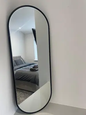 a mirror on a table with a bed in a bedroom at The Crescent-Modern Coastal Home in Blackpool