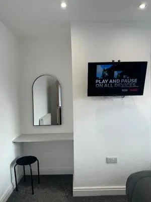 a mirror on a wall next to a table with a stool at The Crescent-Modern Coastal Home in Blackpool