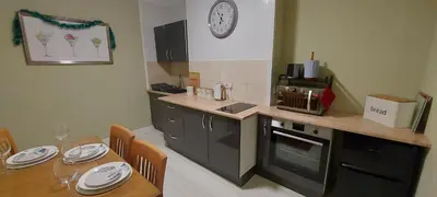 a kitchen with a table and a clock on the wall at The Enigma - 2 Master bedrooms sleeps 6 in Blackpool