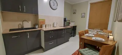 a kitchen with a table and a clock on the wall at The Enigma - 2 Master bedrooms sleeps 6 in Blackpool