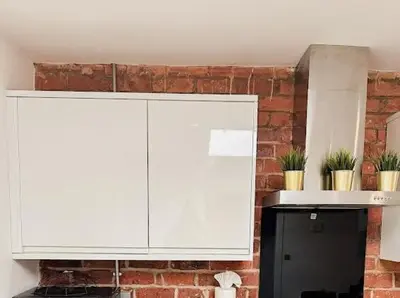 a kitchen with white cabinets and a brick wall at Castle Street 2 Bedroomed Next to The IVY in Liverpool