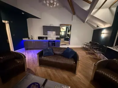 a living room with leather couches and a kitchen at The Loft At One Luxury Penthouse in Wigan
