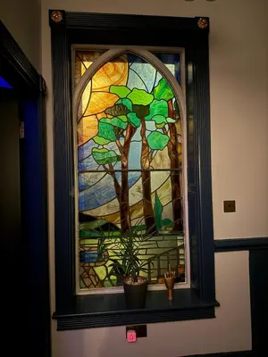 a stained glass window with a plant on a shelf at The Loft At One Luxury Penthouse in Wigan
