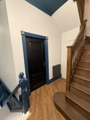 a hallway with a black door and stairs at The Loft At One Luxury Penthouse in Wigan
