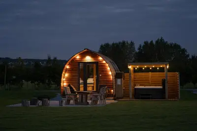 a wooden cabin with a table and chairs in the grass at Ribble Valley by Wigwam Holidays in Langho
