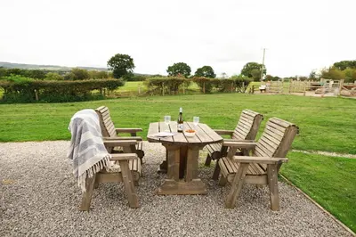 a wooden picnic table with two chairs and a table with wine glasses at Ribble Valley by Wigwam Holidays in Langho