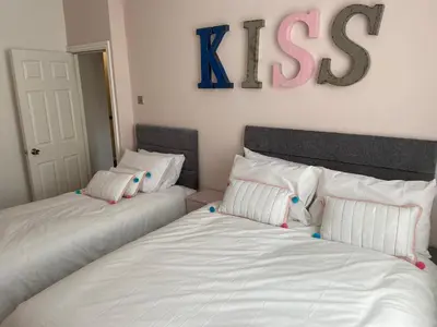 two beds in a bedroom with a kiss sign on the wall at Blackpool - 4 Beds - Sleeps 10 - Pet Friendly in Blackpool