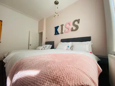 a bedroom with a large bed with a kiss sign on the wall at Blackpool - 4 Beds - Sleeps 10 - Pet Friendly in Blackpool