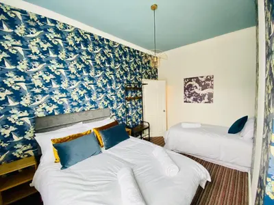 a bedroom with two beds and a blue and white wallpaper at Blackpool - 4 Beds - Sleeps 10 - Pet Friendly in Blackpool