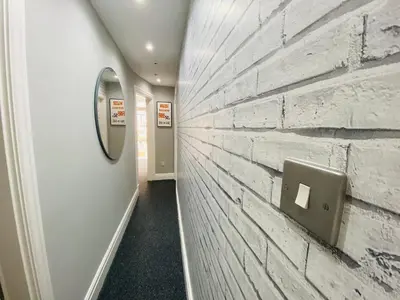 a hallway with a white brick wall with a paper towel dispenser at Blackpool - 4 Beds - Sleeps 10 - Pet Friendly in Blackpool