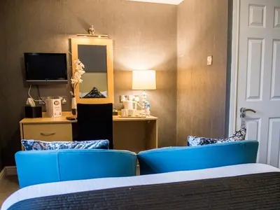 a hotel room with two blue chairs and a mirror at Briardene in Blackpool