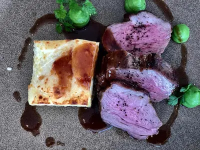a piece of meat with a piece of cheese and peas at Briardene in Blackpool