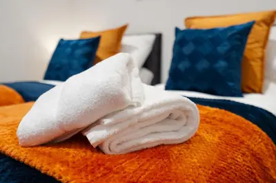 a pile of white towels sitting on top of a bed at Brighton Street Apartment - 2 Bedroom Free Wi-Fi and Parking in Wallasey