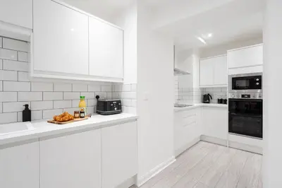 a white kitchen with white cabinets and a plate of food at Brighton Street Apartment - 2 Bedroom Free Wi-Fi and Parking in Wallasey