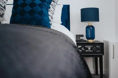 a bed with blue pillows and a blue lamp on a night stand at Brighton Street Apartment - 2 Bedroom Free Wi-Fi and Parking in Wallasey
