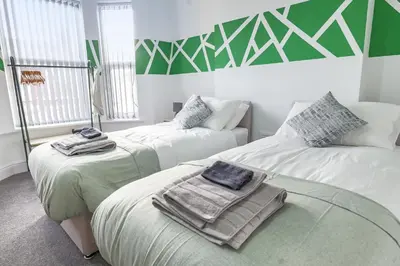 two beds with towels on them in a room at Contractor Luxury Home - Long Stays - 4 Bedrooms - Sleep 8 - Zip & Link Beds - Ultra Fast WiFi - Free Parking in Birkenhead